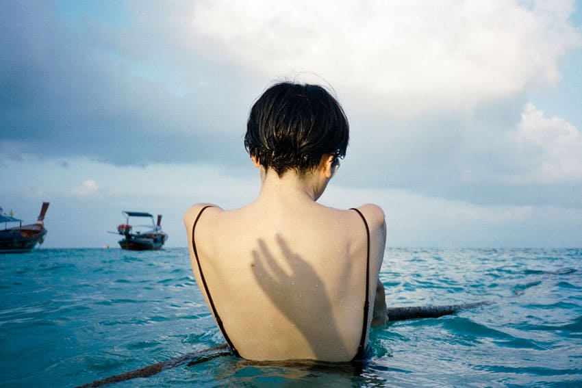 35mm film image of a shadow of a hand on a woman's back in the ocean - Fine Art Series by Nick Prideaux on Shoot It With Film