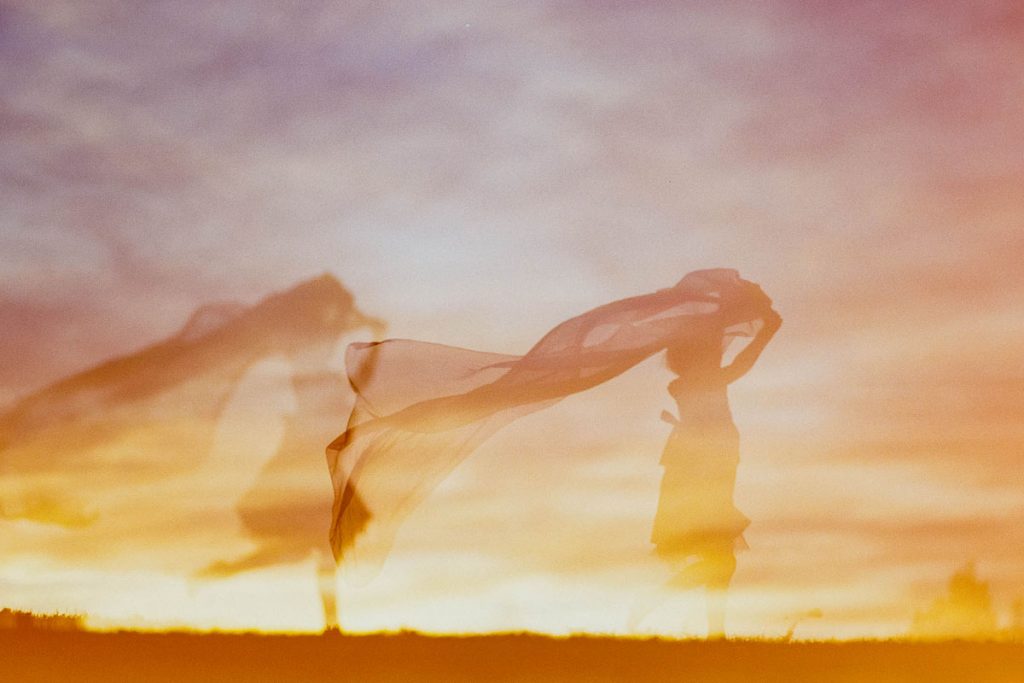 Film double exposure of a girl running through a field