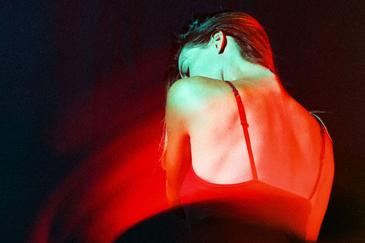 35mm film image with a portrait lit in blue light and a streak of movement in red.